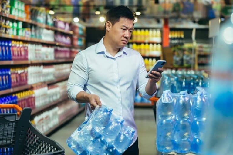 Food crisis, drinking water shortage, Asian man in supermarket buying bottled water